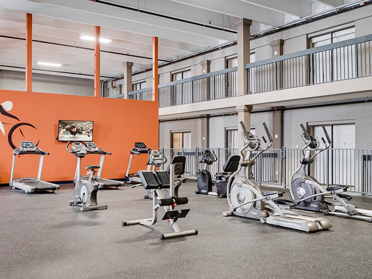 large fitness room with lots of equipment and orange wall